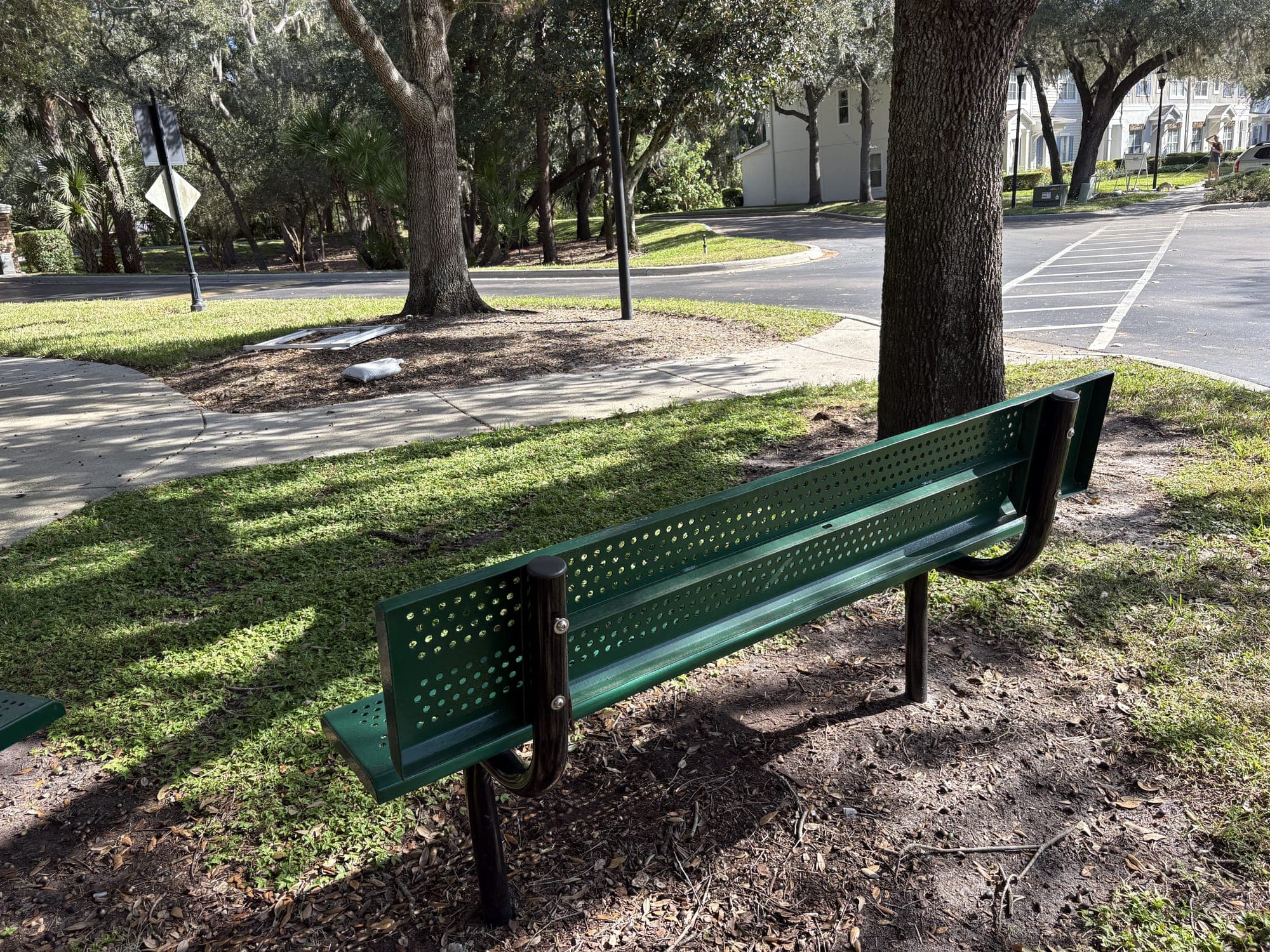 The second bench under the oak, by the sidewalk.