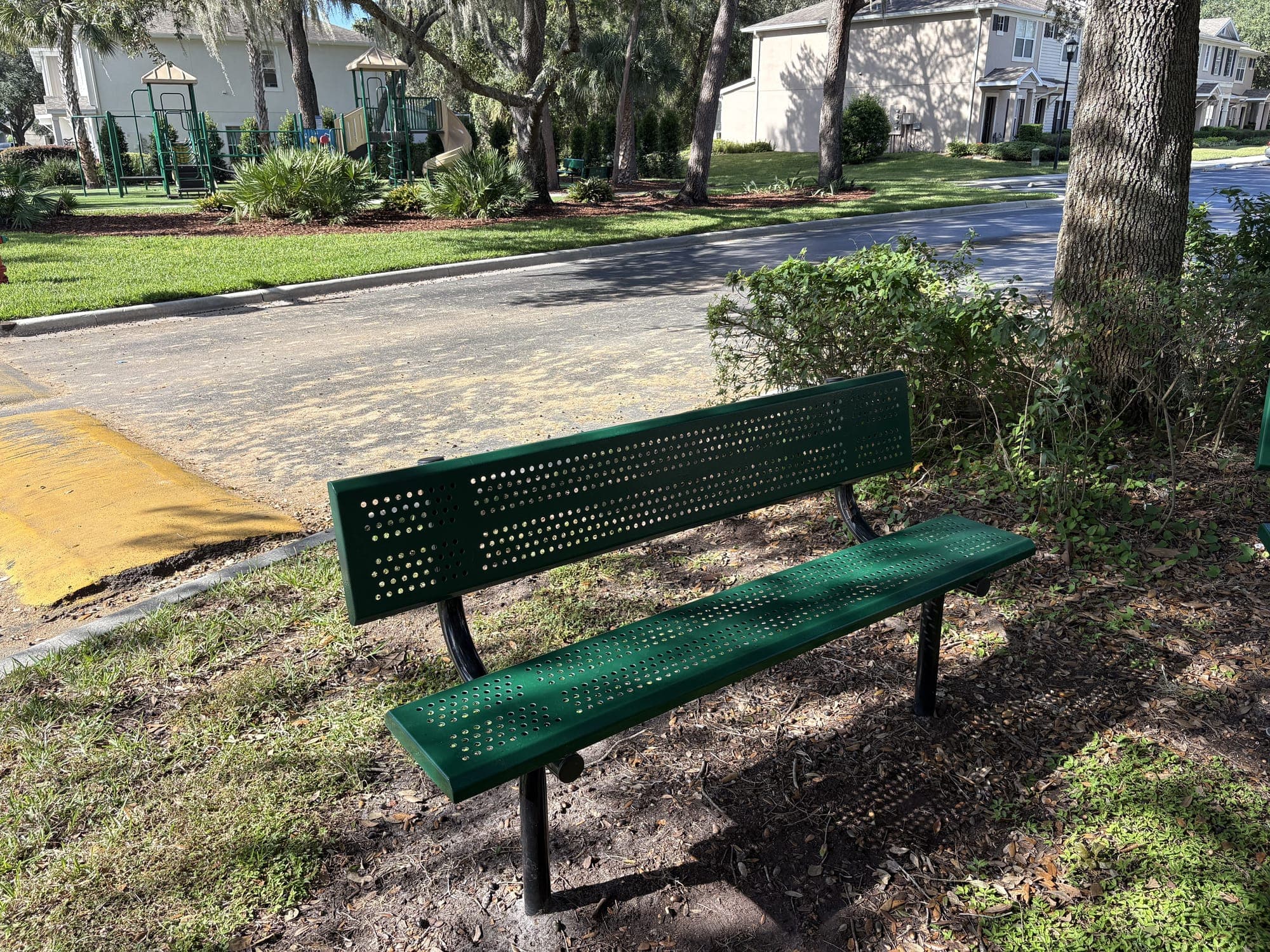 The second bench from the side, a speed hump and the street behind it.