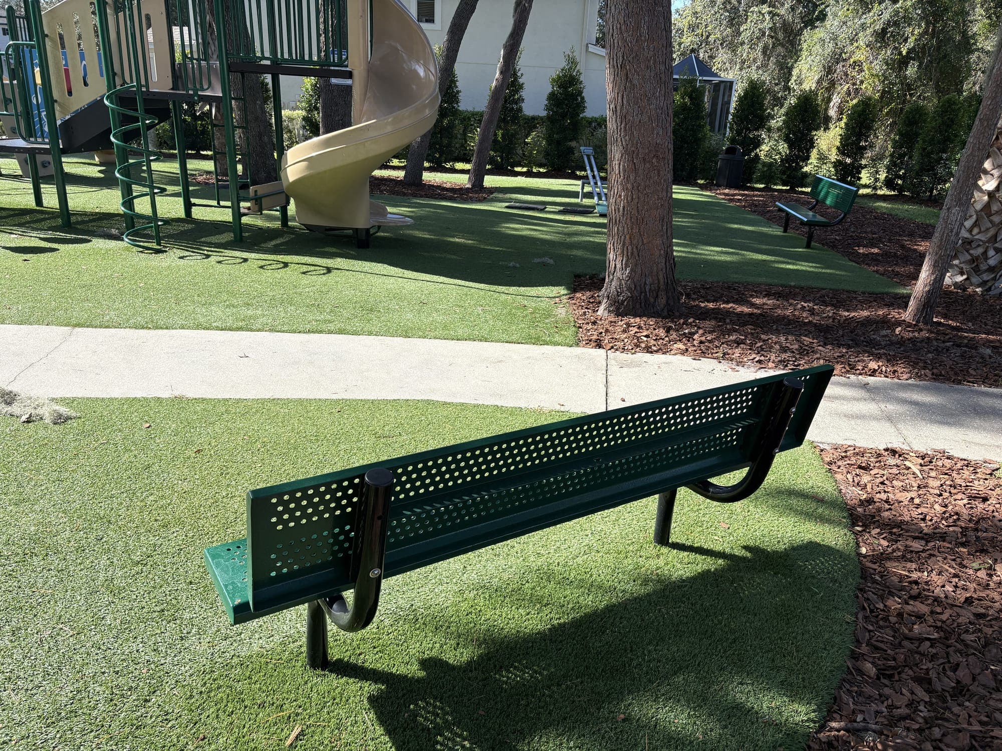 The bench from behind, facing the path and the playground slides.